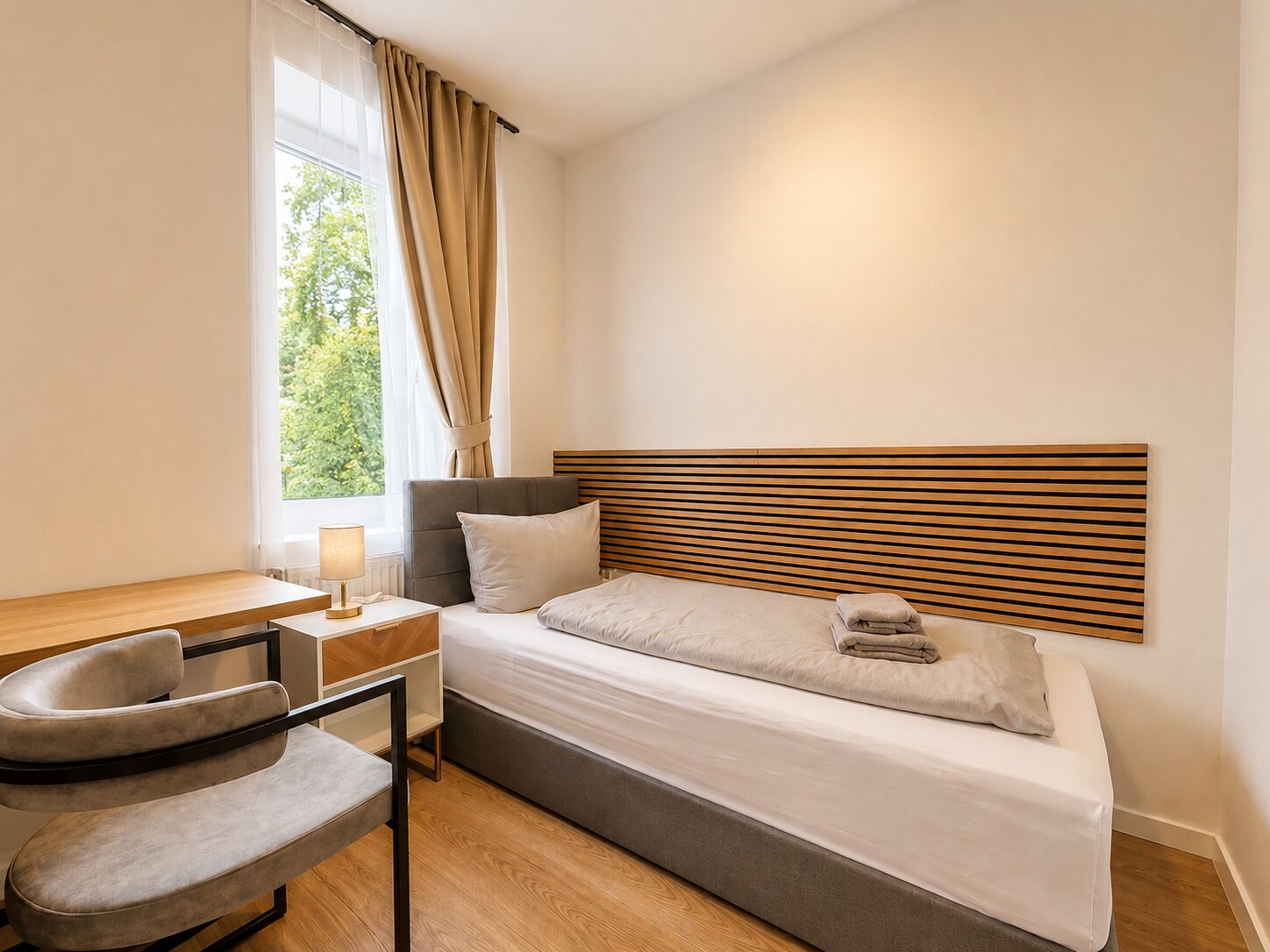 Helles Einzelzimmer mit Bett und Schreibtisch am Fenster
